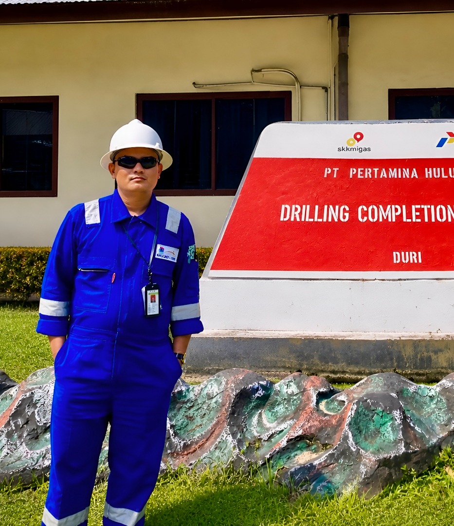 Rizky Mahreza in blue coveralls, hard hat and ID badge at a PT Pertamina Hulu Rokan drilling completion site in Duri